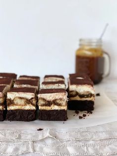 there are many brownies with white and chocolate frosting on the table next to each other