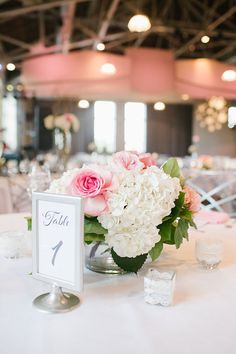 a centerpiece with flowers and greenery sits on a table at a wedding reception