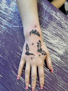 a woman's hand with bats and stars tattoo on the left side of her palm