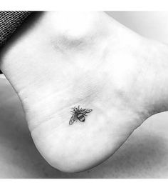 a black and white photo of a bee tattoo on the foot, with its wings spread out