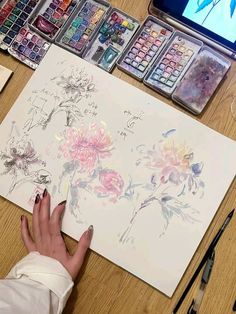 someone is drawing flowers on paper with watercolors