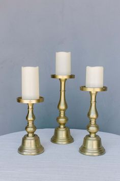 three brass candlesticks on a white table