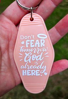 a hand holding a pink keychain that says don't fear tomorrow god is already here