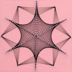 a star made out of string on a pink wall with white dots and black lines