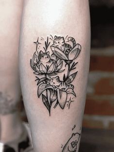 a black and white tattoo on the leg of a woman with flowers around her ankles