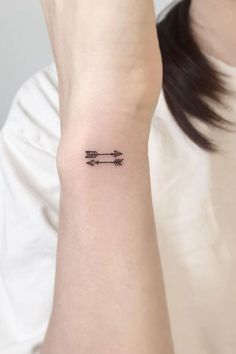 a woman's arm with an arrow tattoo on it