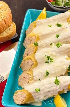 a blue plate topped with meat covered in gravy next to bread and salad