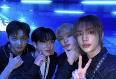 group of young men posing for the camera in front of a blue wall with their fingers up