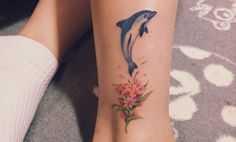 a woman's foot with a dolphin tattoo on her left leg and flowers in the middle