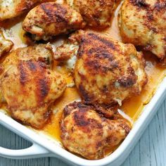 chicken thighs in a white casserole dish on a wooden table with text overlay