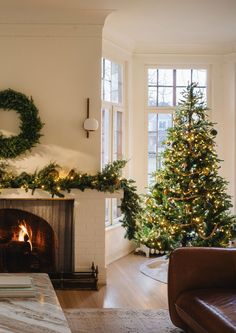 a living room filled with furniture and a fire place next to a christmas tree in front of a window