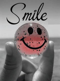 a person holding up a smiley face bubble with the words smile at you on it