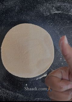 a hand is pointing at an uncooked pizza dough