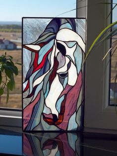 a stained glass window with a cow head on it's side and a potted plant next to it