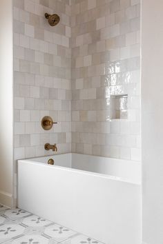 a white bath tub sitting inside of a bathroom next to a shower head and faucet