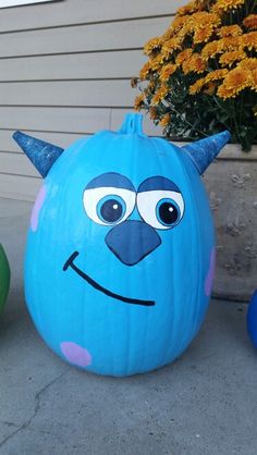 two pumpkins with faces painted on them sitting in front of a flower planter