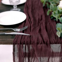 the table is set with white plates and silverware, along with red cloth draped over it