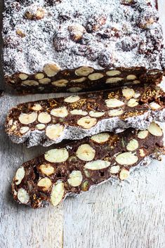 three pieces of chocolate and almond bread on a wooden table, with powdered sugar