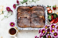 a cake sitting on top of a pan covered in powdered sugar next to flowers