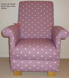 a purple chair with white polka dots on it in front of a wall and carpet