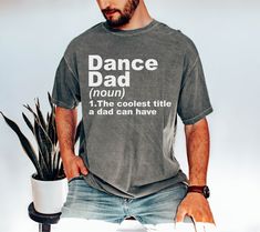 a man is sitting down with his hands in his pockets while wearing a t - shirt that says dance dad