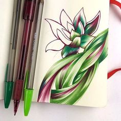 a notebook with two pens and some colored pencils next to it