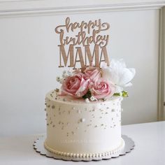 a white cake topped with pink flowers and a wooden happy birthday mama sign on top