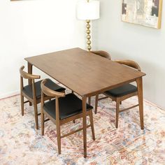 a wooden table with two chairs and a lamp on top of it in front of a painting