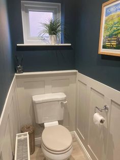 a white toilet sitting in a bathroom next to a radiator and window with blue walls