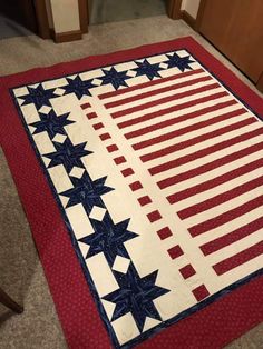 a red, white and blue quilt with stars on the bottom is laying on the floor