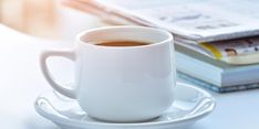 a cup of coffee sitting on top of a saucer next to a stack of books