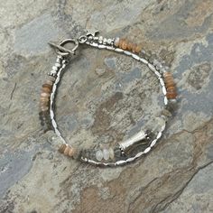 This double stranded bracelet is handmade using natural gemstones and the highest quality Sterling Hill Tribe silver. One strand is multi colored moonstone rondelles and a large Hill Tribe silver bead at the center. The other strand is Hill Tribe liquid silver, each separated with tiny silver beads. Finished with a silver Hill Tribe toggle clasp and star charm. Multi moonstone: 4mm Sterling silver center bead: 12 x 7mm Sterling silver toggle: 12mm Your jewelry will arrive in a cotton lined kraft box within a padded postal envelope. I use USPS first class mail. This usually takes 3 to 5 days to ship. International orders outside of the U.S. will take 8 to 15 days to ship. To see more from East Village Jewelry~ http://eastvillagejewelry.etsy.com All orders ship out within 24 hours, excluding Silver Rondelle Gemstone Beaded Bracelets, Silver Gemstone Bead Rondelle Bracelets, Silver Rondelle Bracelets With Natural Stones, Silver Rondelle Bracelets With Gemstone Beads, Silver Double Strand Beaded Bracelets With Gemstones, Silver Double Strand Bracelets With Gemstone Beads, Silver Double Strand Bracelet With Natural Stones, Silver Bracelets With Natural Stones And Round Beads, Silver Beaded Bracelets With Natural Stones