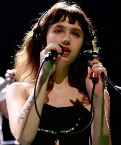 a woman with headphones on singing into a microphone