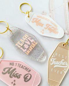 three different keychains that say best teacher ever and one has a name tag on it