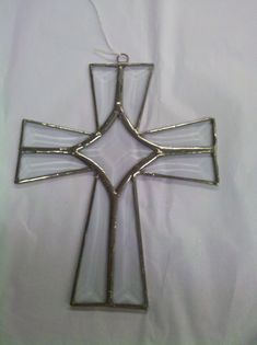 a glass cross ornament hanging on a white sheet