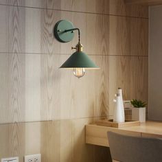 a green light hanging from the side of a wooden wall next to a table and chair