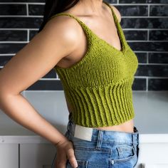 a woman standing in front of a brick wall with her hands on her hips and looking at the camera