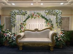 a white couch sitting in front of a window covered in flowers and greenery on display