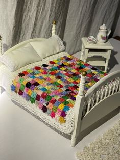 a crocheted granny blanket is on top of a bed with white sheets and pillows