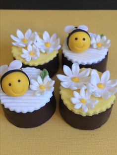 four cupcakes decorated to look like bees and daisies