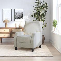 a white chair sitting in front of a window on top of a wooden floor next to a potted plant