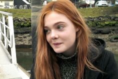 a woman with red hair standing on a bridge