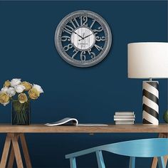 a clock that is on the side of a wall next to a table with flowers