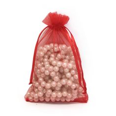 a bag filled with lots of pink pearls on top of a white table next to a red ribbon