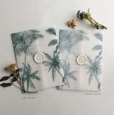 two palm trees printed napkins on top of each other next to dried flowers and leaves