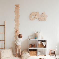 a little boy is playing with the growth chart on the wall above his bed in this child's bedroom