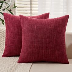 two red pillows sitting on top of a couch