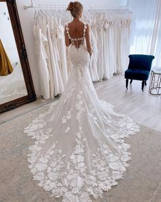 a woman standing in front of a mirror wearing a wedding dress with flowers on it