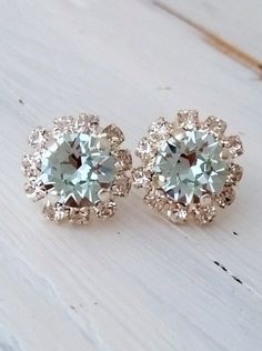 two pairs of diamond earrings sitting on top of a wooden table