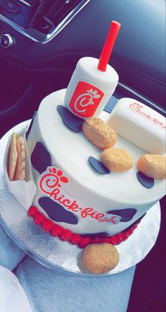 a cake that is sitting on top of a table in a car with crackers and soda